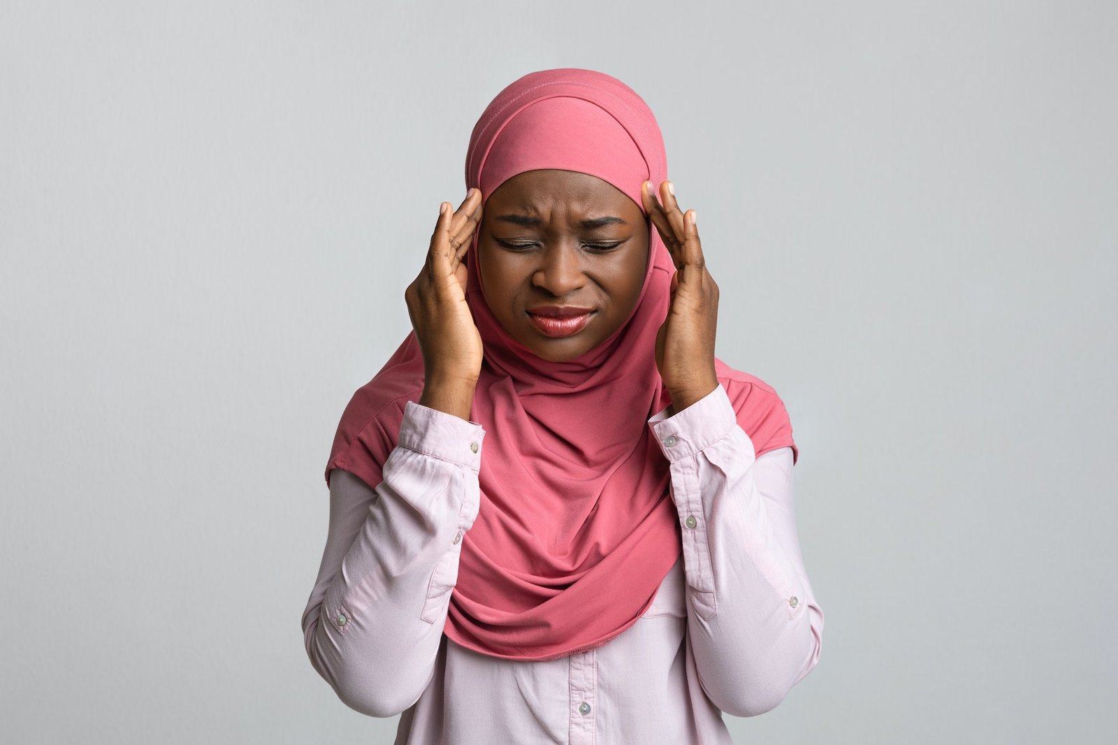 Upset black lady in hijab having headache, grey background